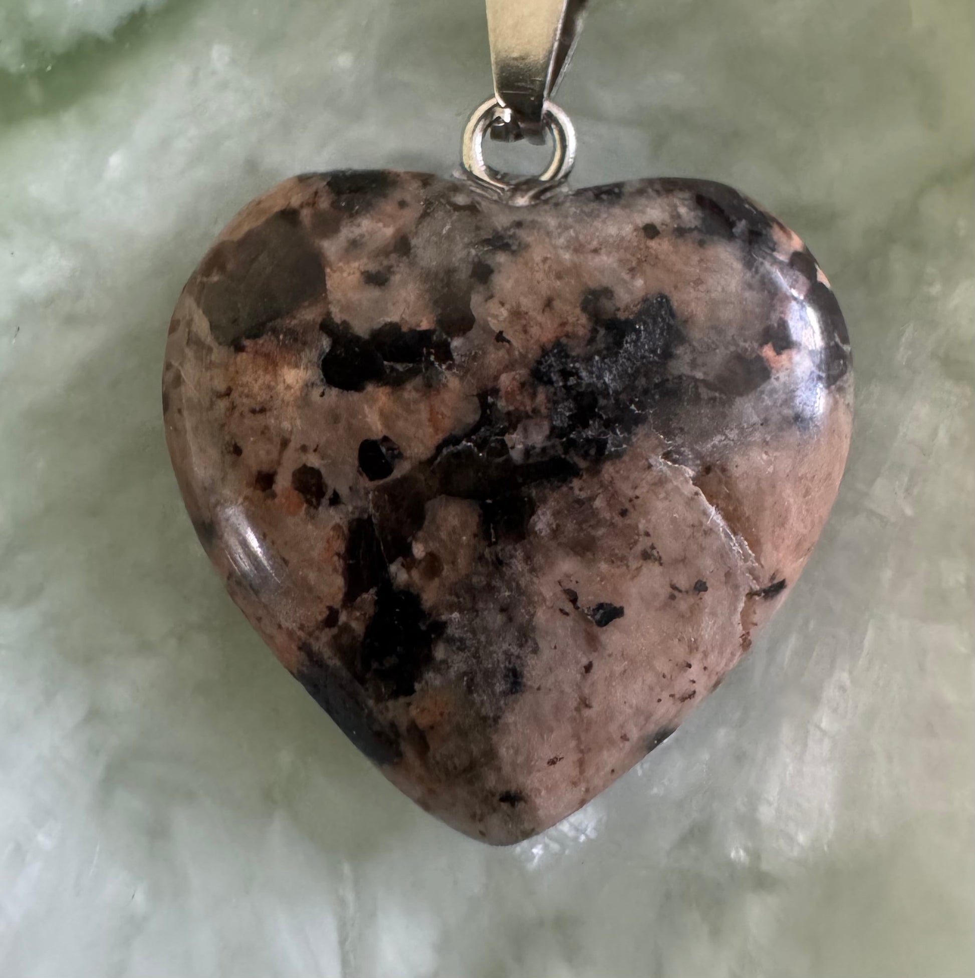 Heart-shaped rhodochrosite pendant with silver bail.
