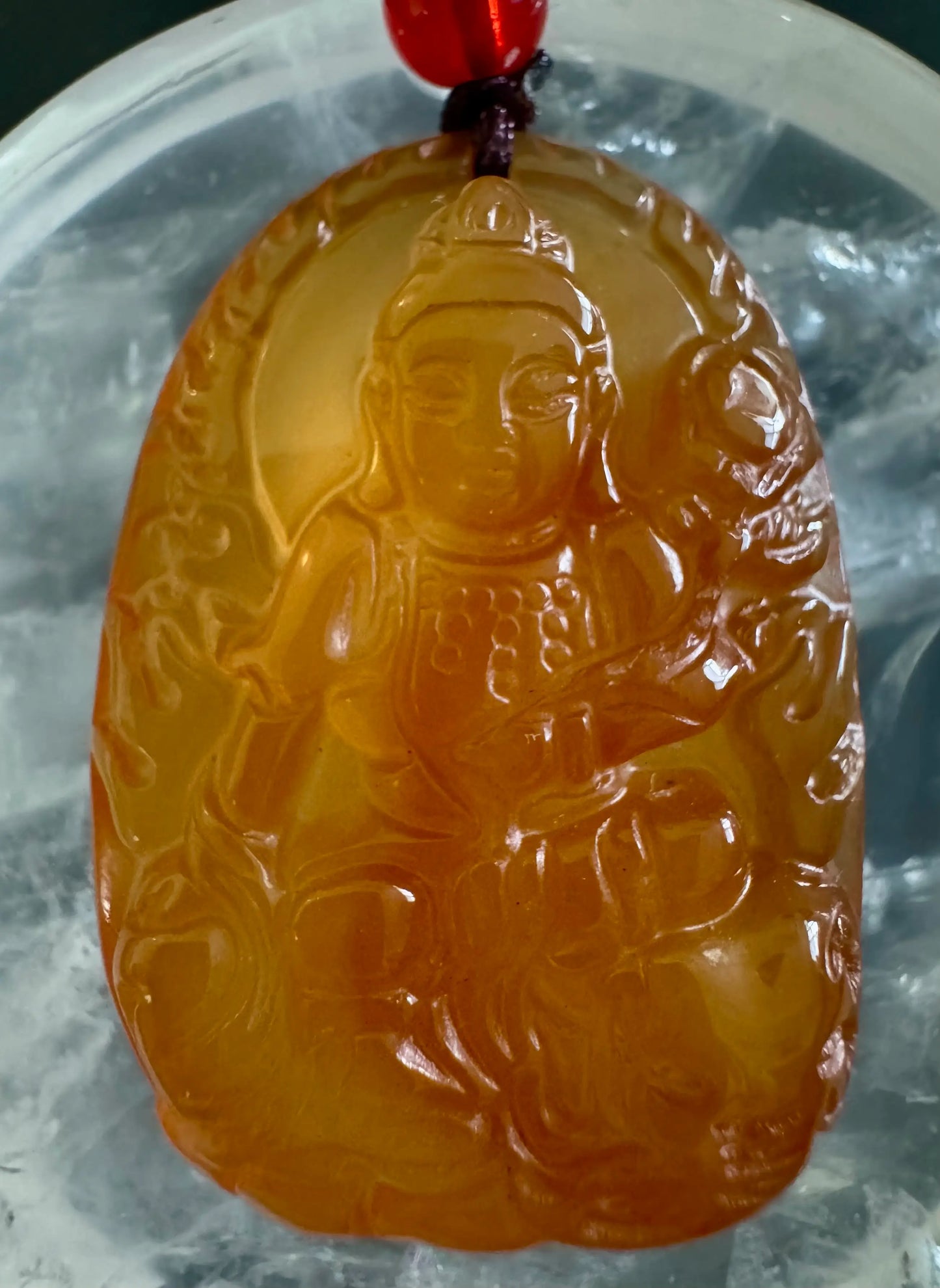 Yellow-orange jade pendant with carved seated figure.