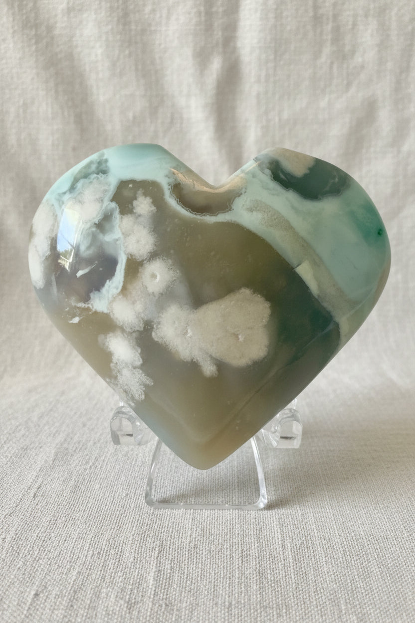 close up of flower agate carved heart, greens, blues, browns and white. 