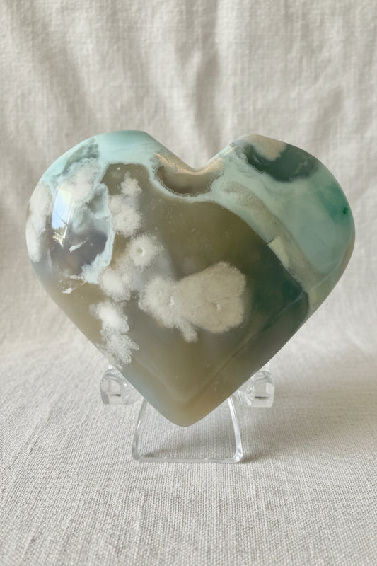 close up of flower agate carved heart, greens, blues, browns and white. 