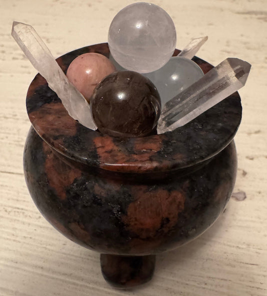 Close-up of a dark stone cauldron filled with crystal spheres and points.