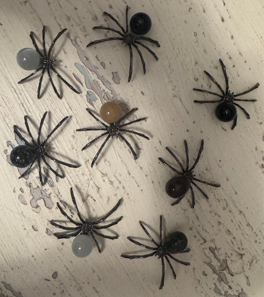 Eight decorative spiders with bead bodies on a weathered white surface.