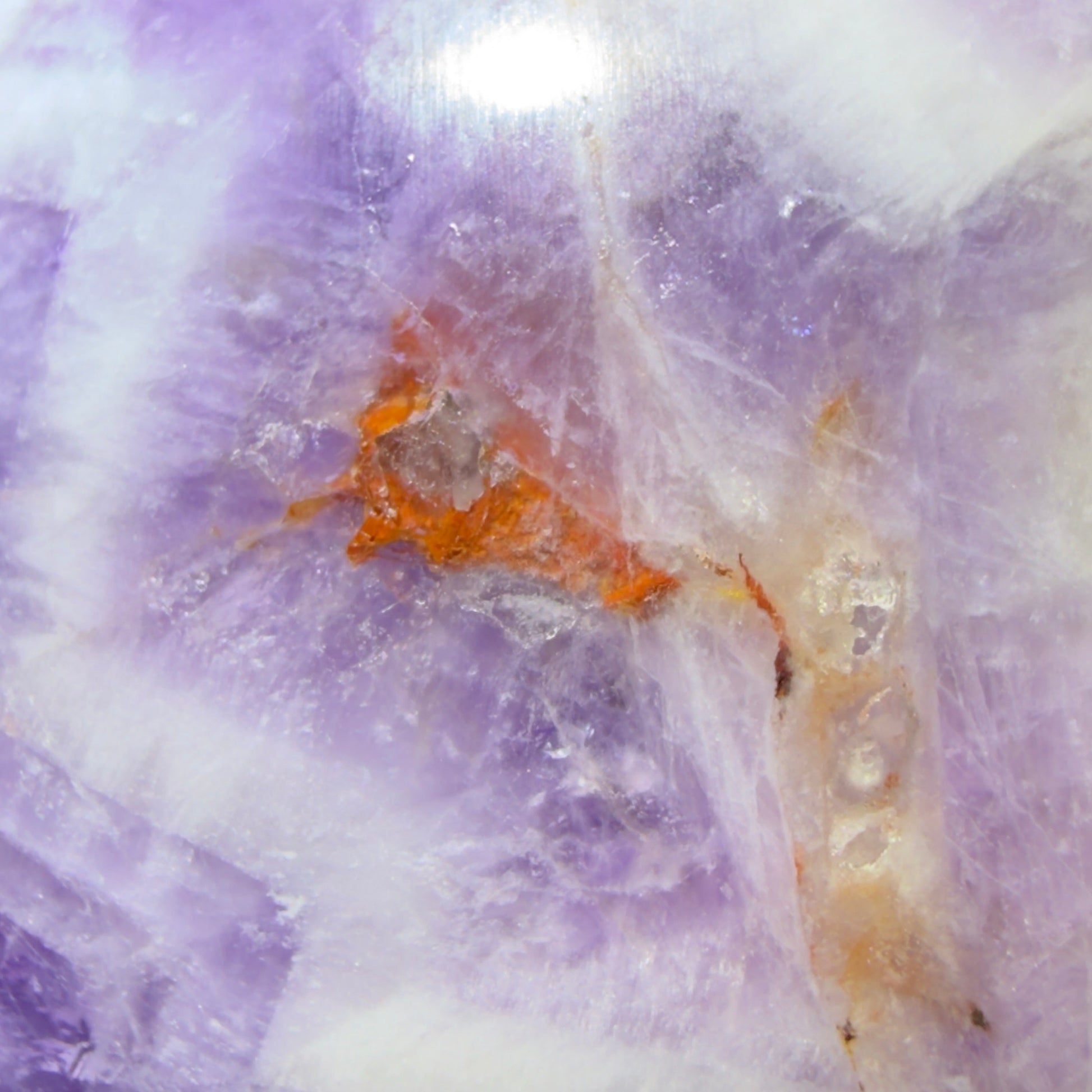close up likely hematite inclusions amethyst sphere purples, oranges, white 