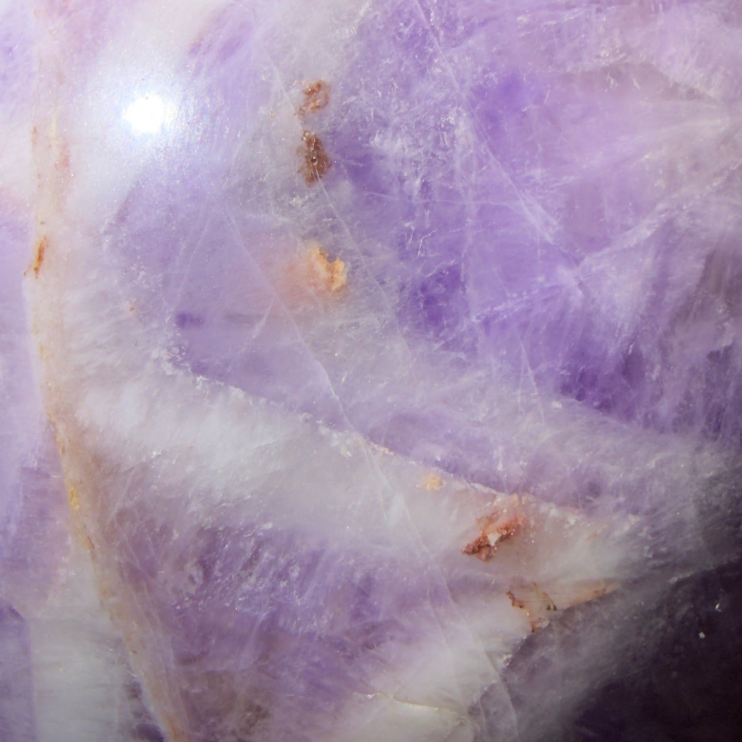 close up rare chevron amethyst sphere with orange and brown iron inclusions most likely hematite light purples, whites 