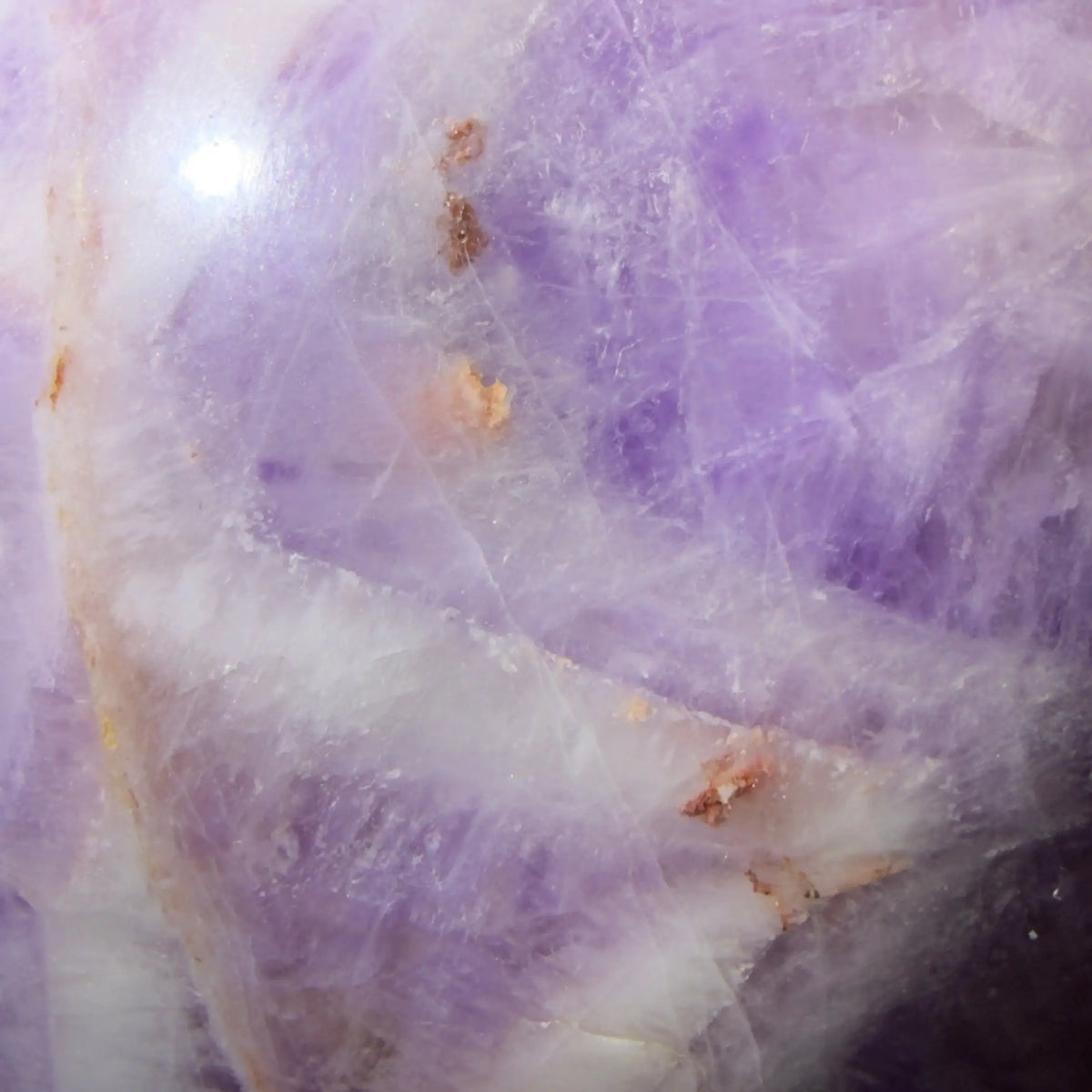 close up rare chevron amethyst sphere with orange and brown iron inclusions most likely hematite light purples, whites 