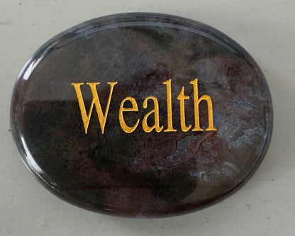Oval, marble-like stone with gold "Wealth" lettering.