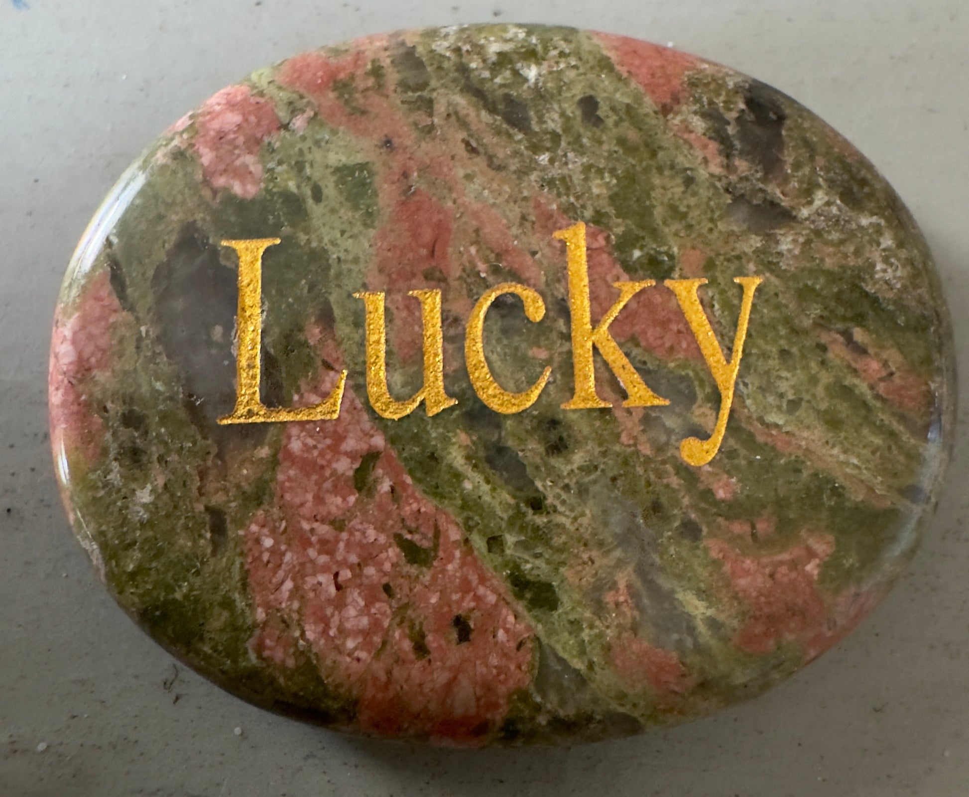 Polished unakite stone with "Lucky" inscription.