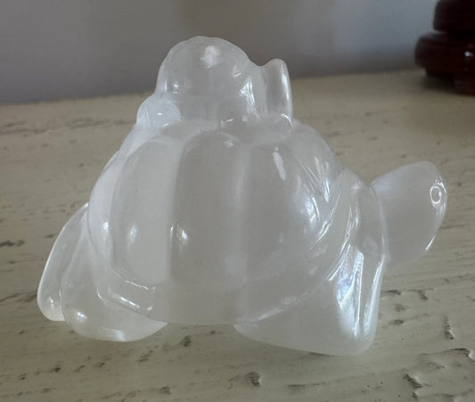 Selenite Polished Carving two turtles on a rustic table 