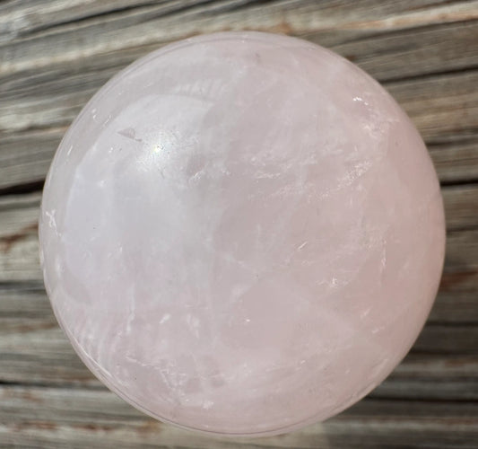 Pink crystal ball on wooden surface.
