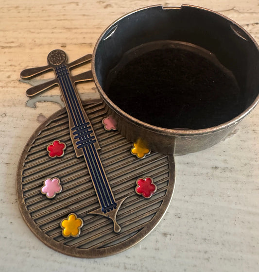Brass Yueqin incense holder with painted flowers close-up