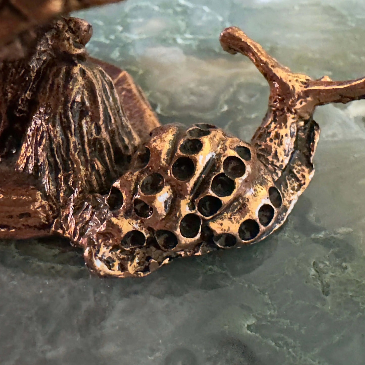 Close-up of a bronze snail figurine.