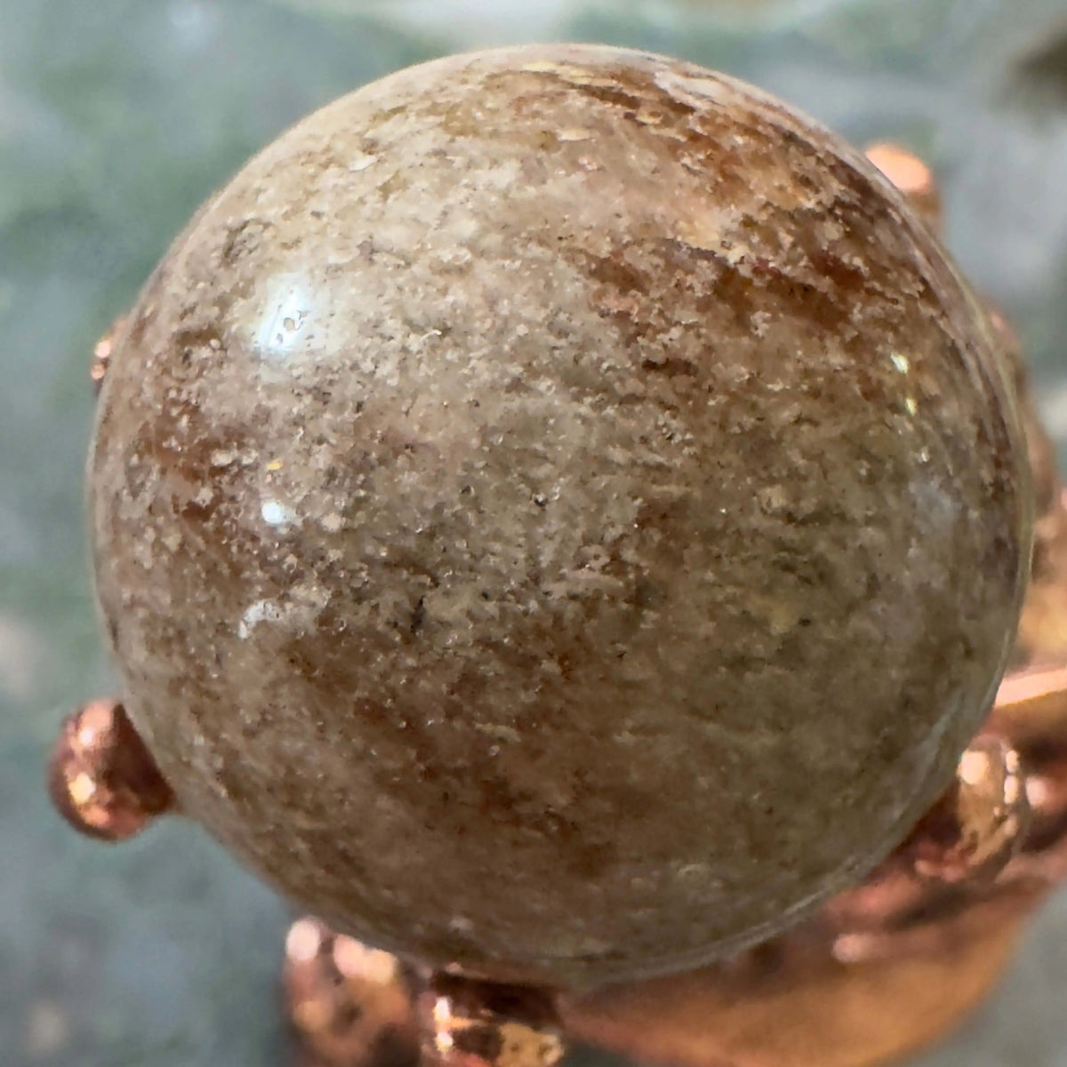 Polished Garden Quartz sphere resting on bronze stand