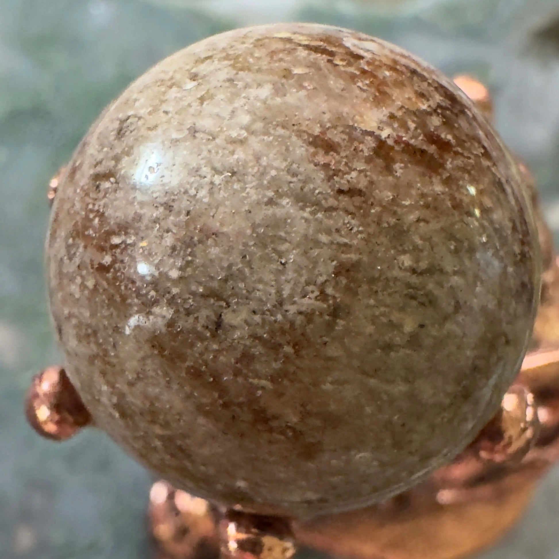 Polished Garden Quartz sphere resting on bronze stand
