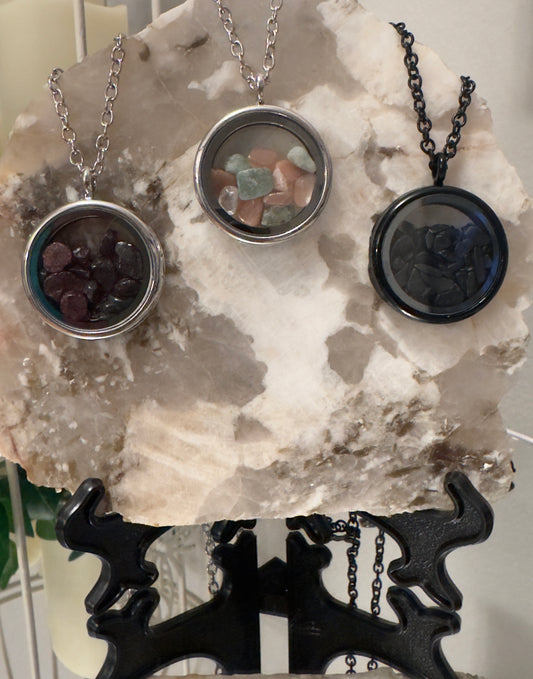 Three gemstone necklaces on a marble slab supported by a black metal stand.