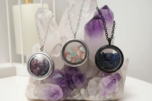 Three gemstone necklaces on a marble slab supported by a black metal stand.