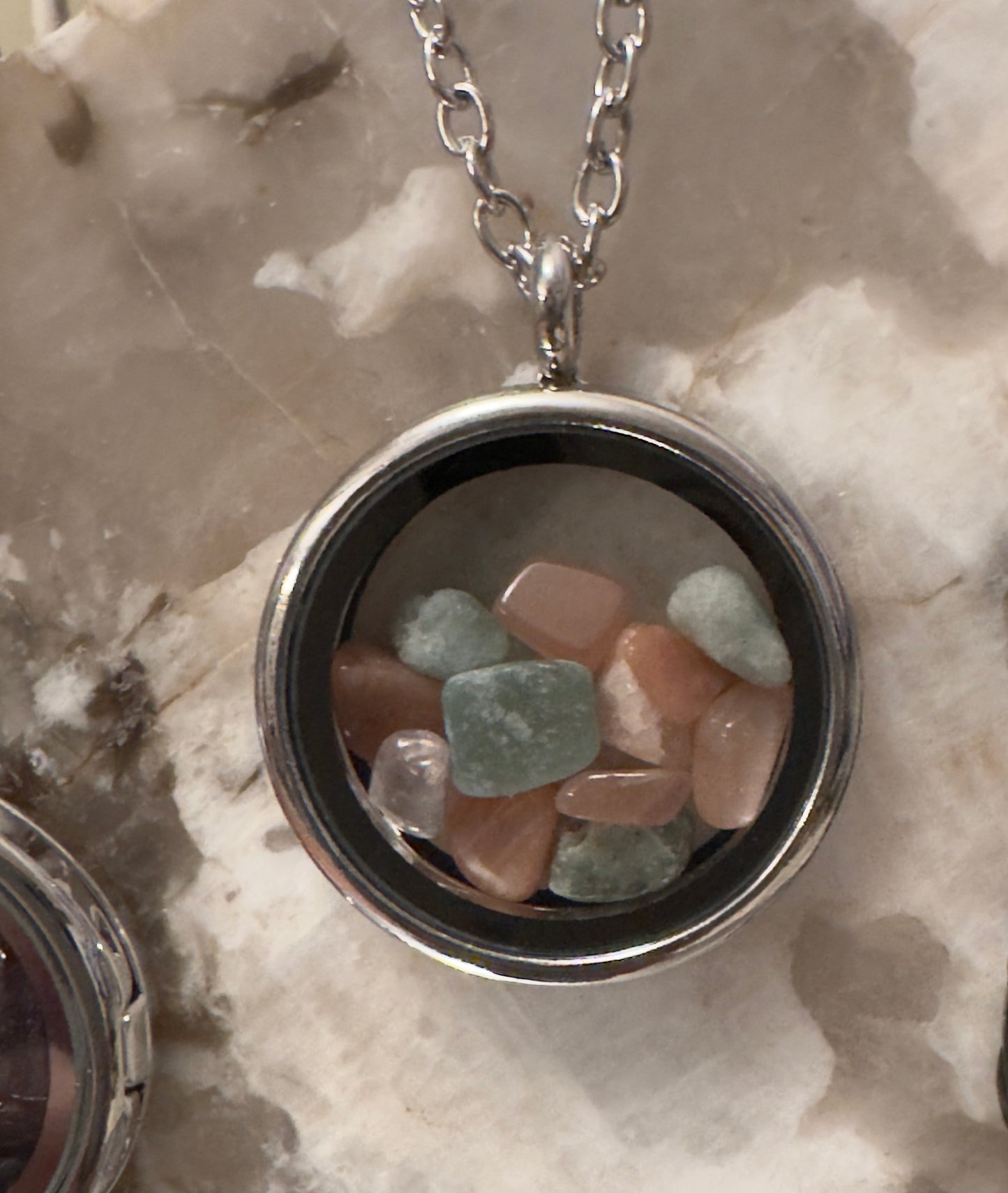 Round silver necklace with pastel-colored gemstones.
