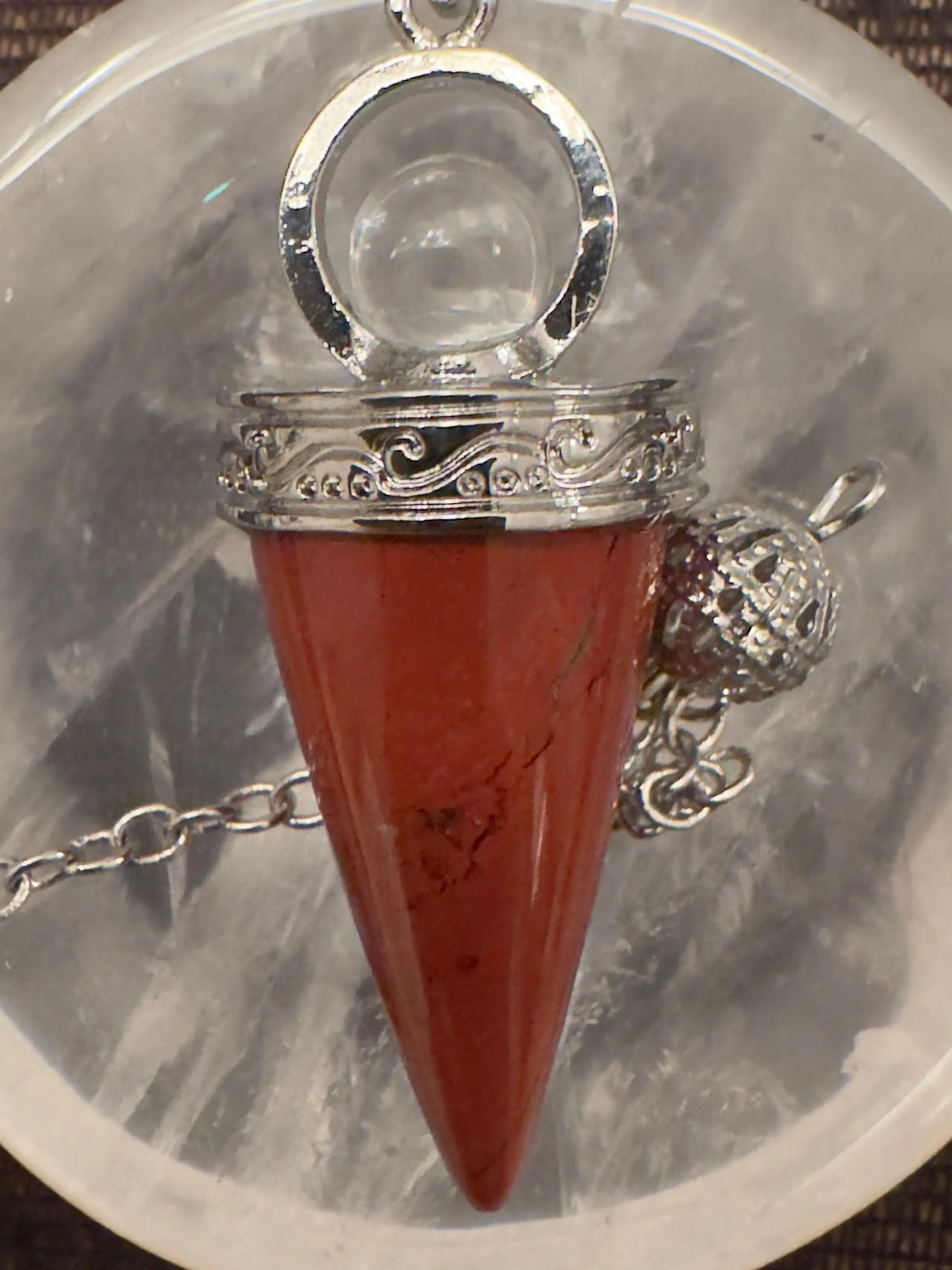 Red crystal pendant with silver chain and filigree details.