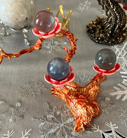 Crystal ball stand with three spheres on a snowflake tablecloth.
