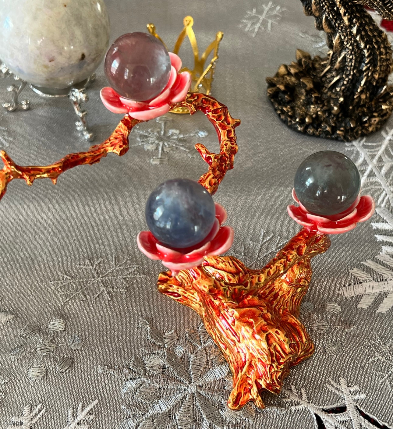 Crystal ball stand with three spheres on a snowflake tablecloth.
