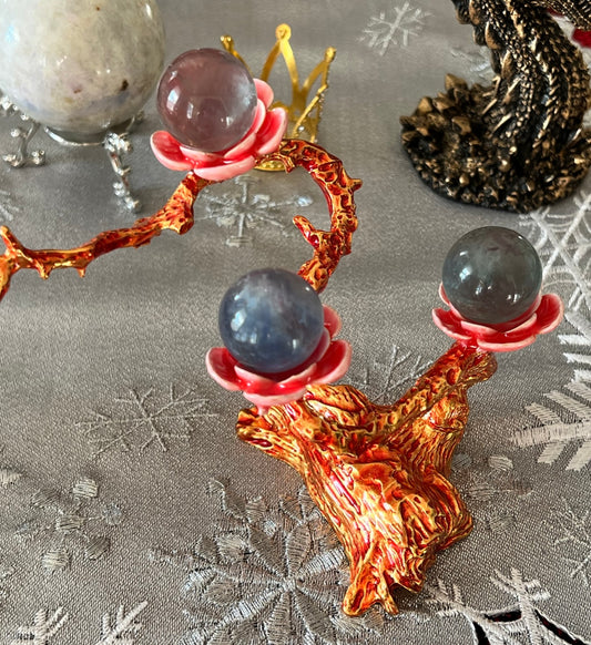 Crystal ball stand with three spheres on a snowflake tablecloth.
