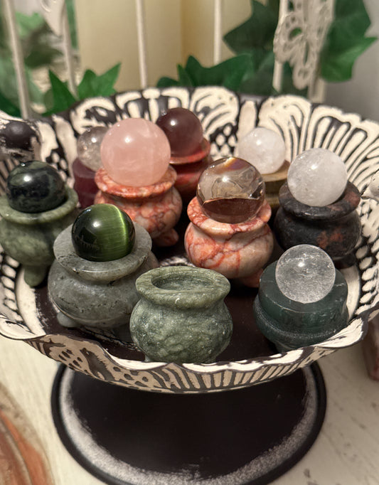 A collection of crystal spheres sitting on miniature stone urns, displayed on a decorative black and white tray.