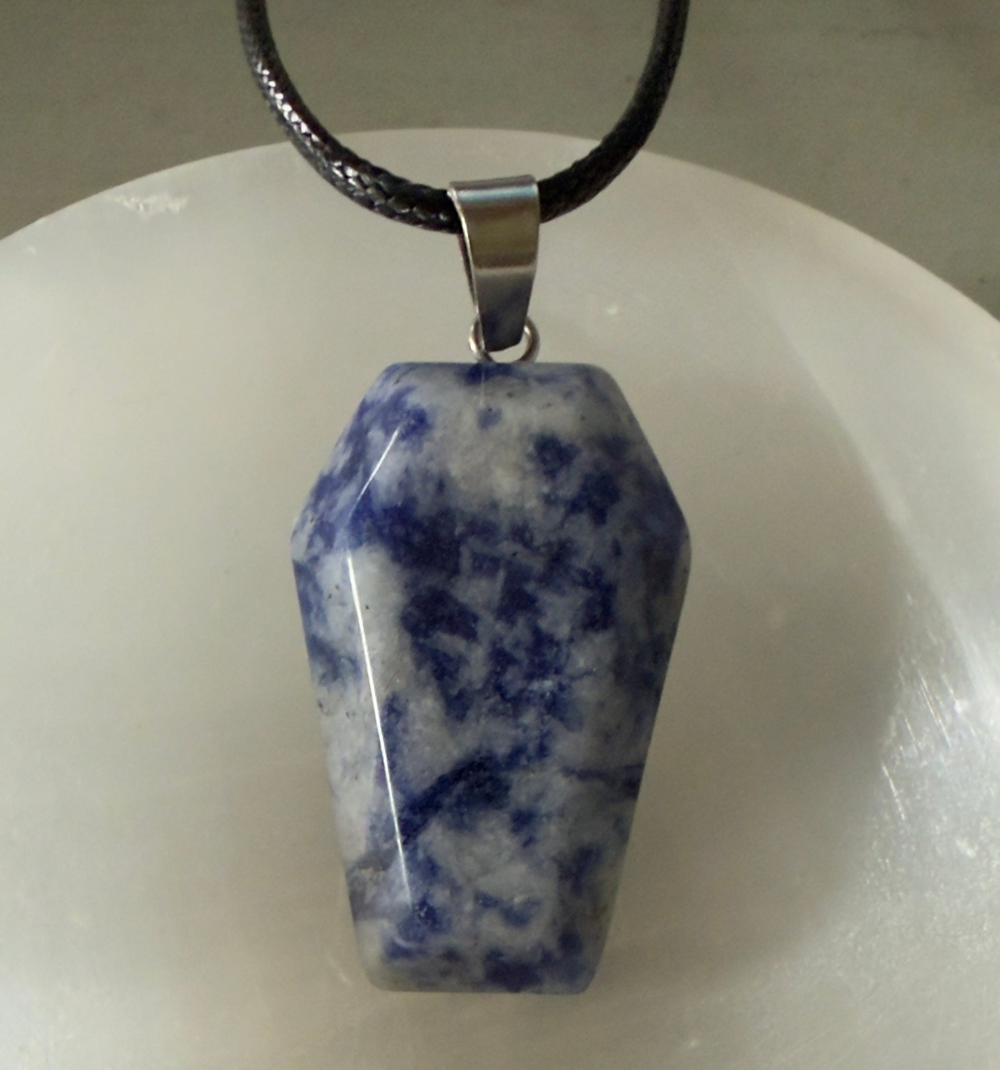 Blue and white coffin-shaped gemstone pendant on a black cord.
