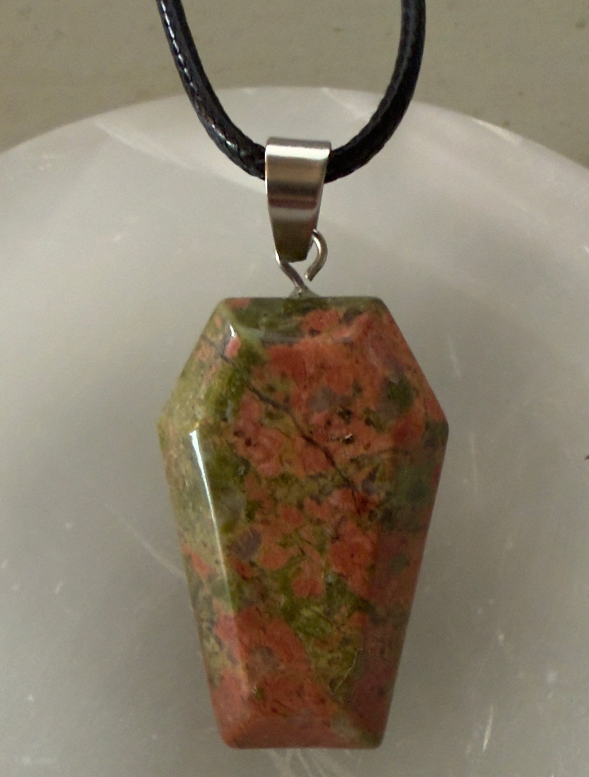 Unakite gemstone pendant with a black cord.