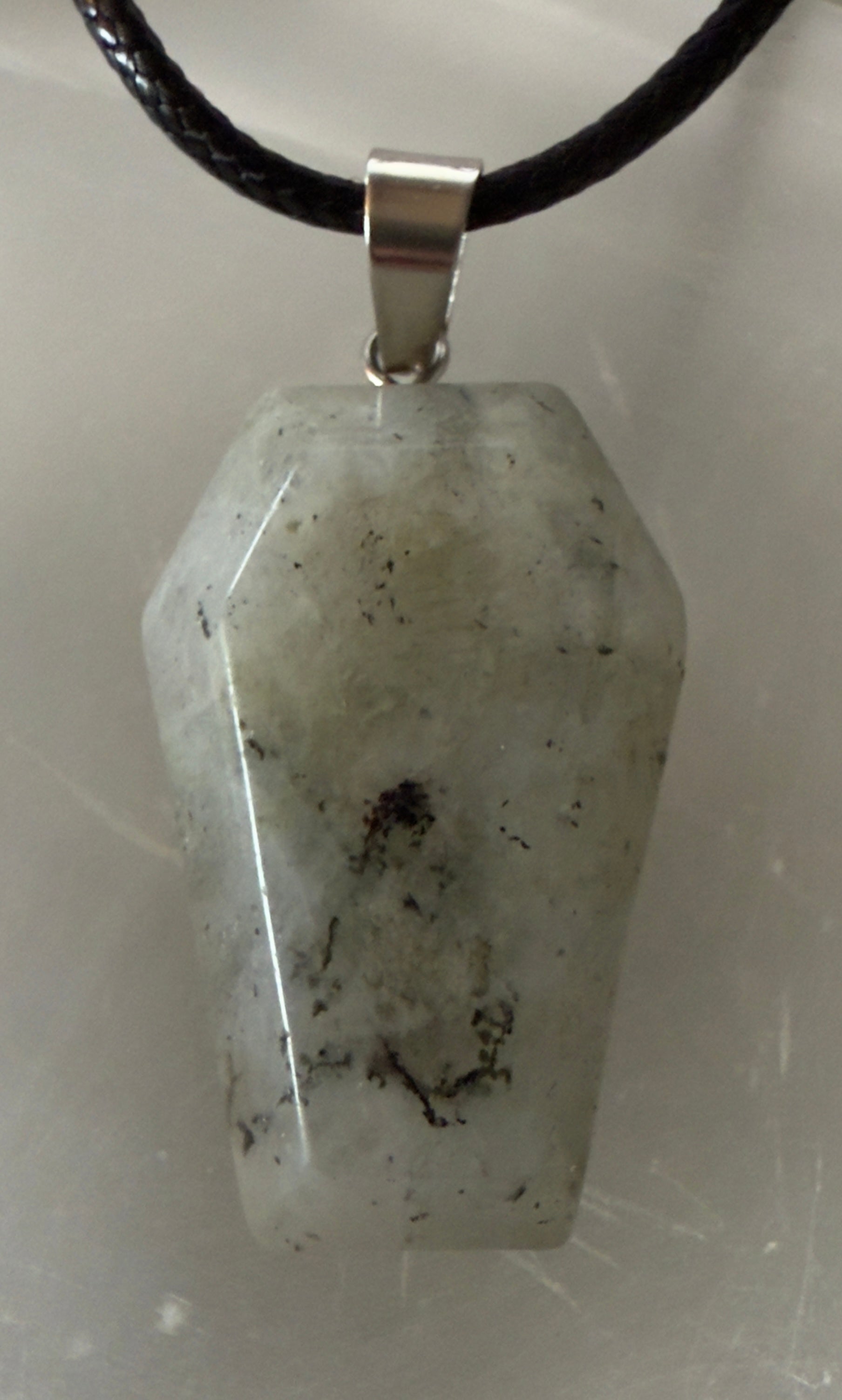 Coffin-shaped moonstone pendant on a black cord.