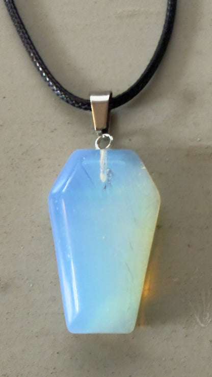 Close-up of a blue and yellow coffin-shaped opal pendant on a black cord.