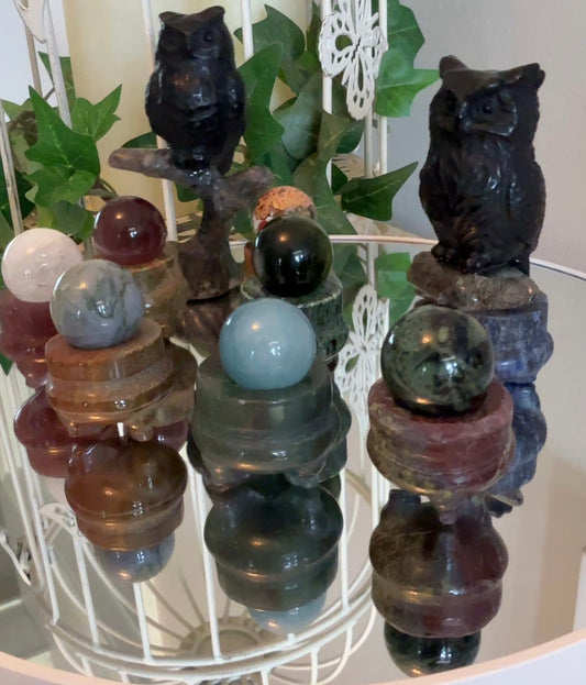 Decorative items with owl statues and crystal balls on a stand.