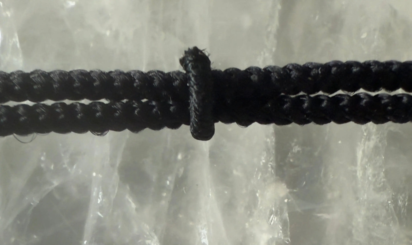 Crystal cross pendant on black braided cord detail view