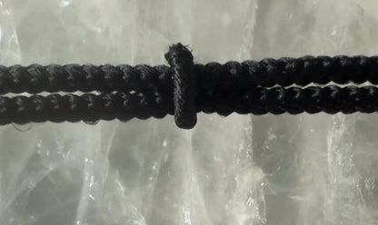 Crystal cross pendant on black braided cord detail view