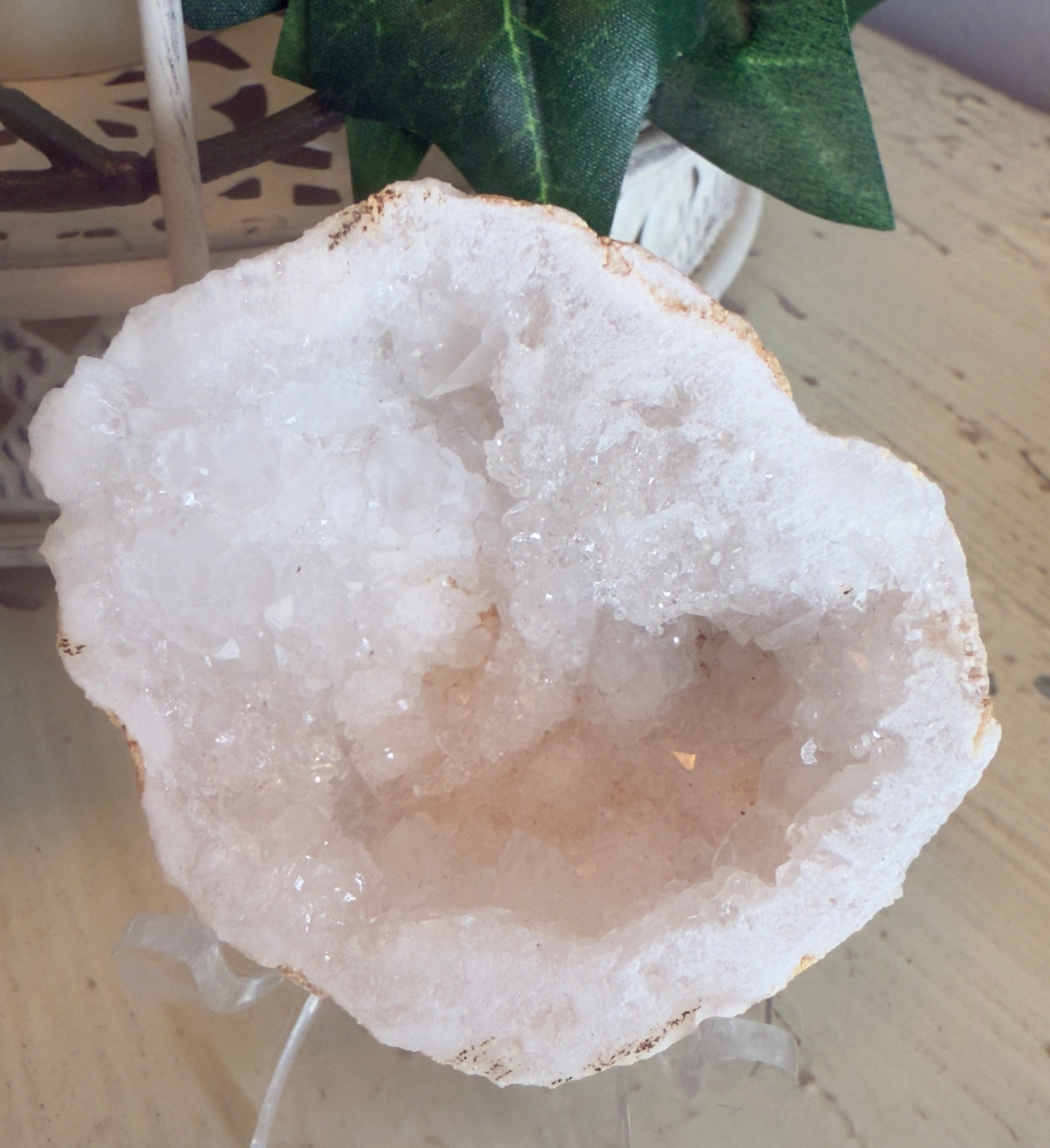 A white quartz geode on a clear stand.