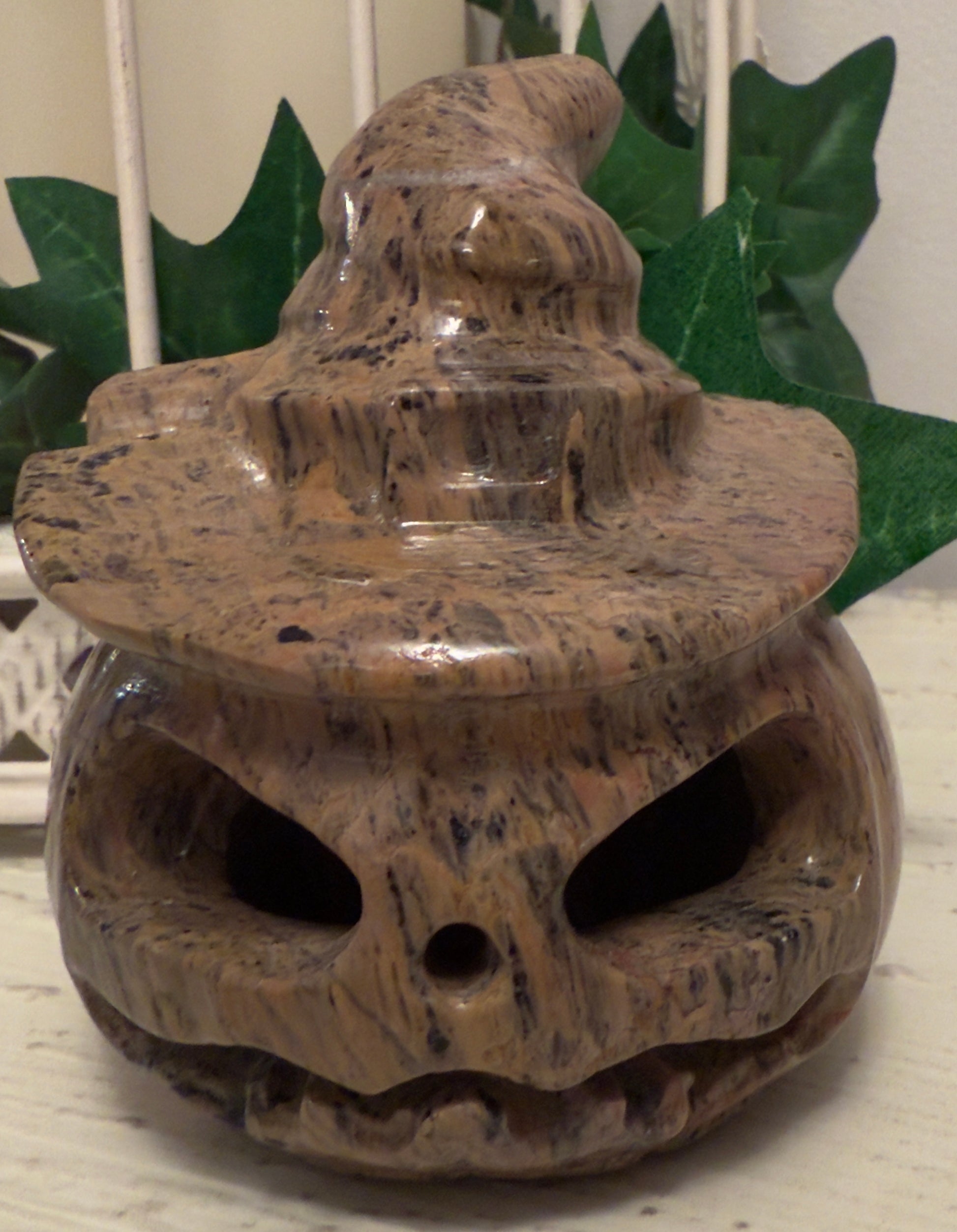 Brown, speckled stone jack-o-lantern with a witch's hat.