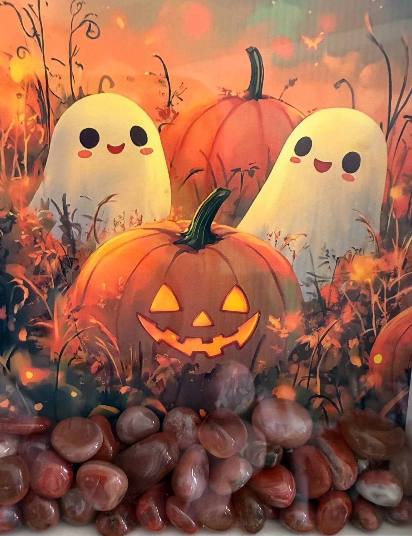 Halloween-themed art featuring pumpkins and ghosts, foregrounded by red agate stones.