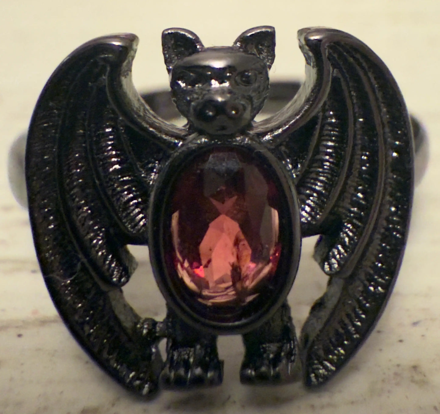 Black metal bat ring with a red gemstone.