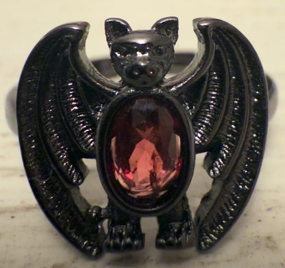Black metal bat ring with a red gemstone.