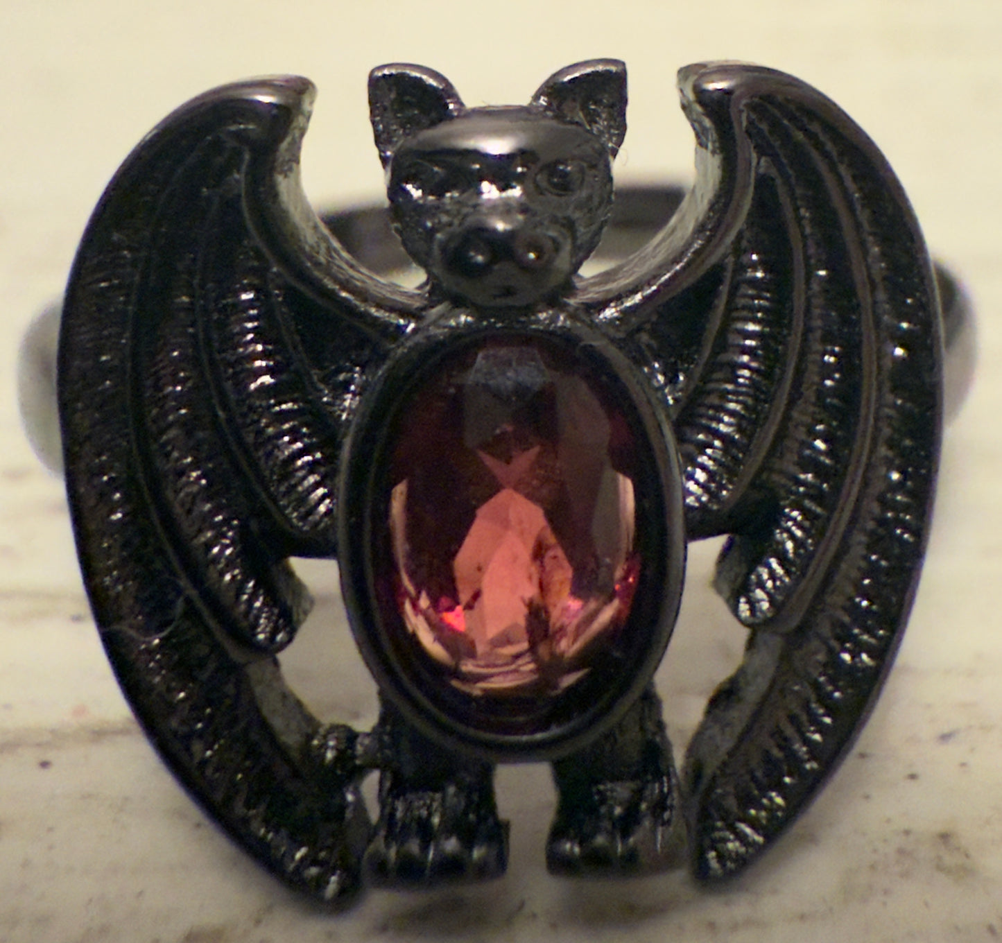 Black metal bat ring with a red gemstone.