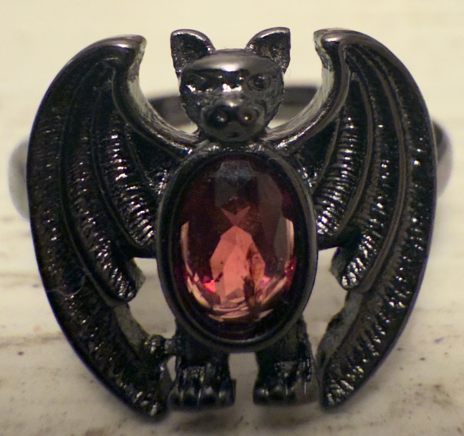 Black metal bat ring with a red gemstone.