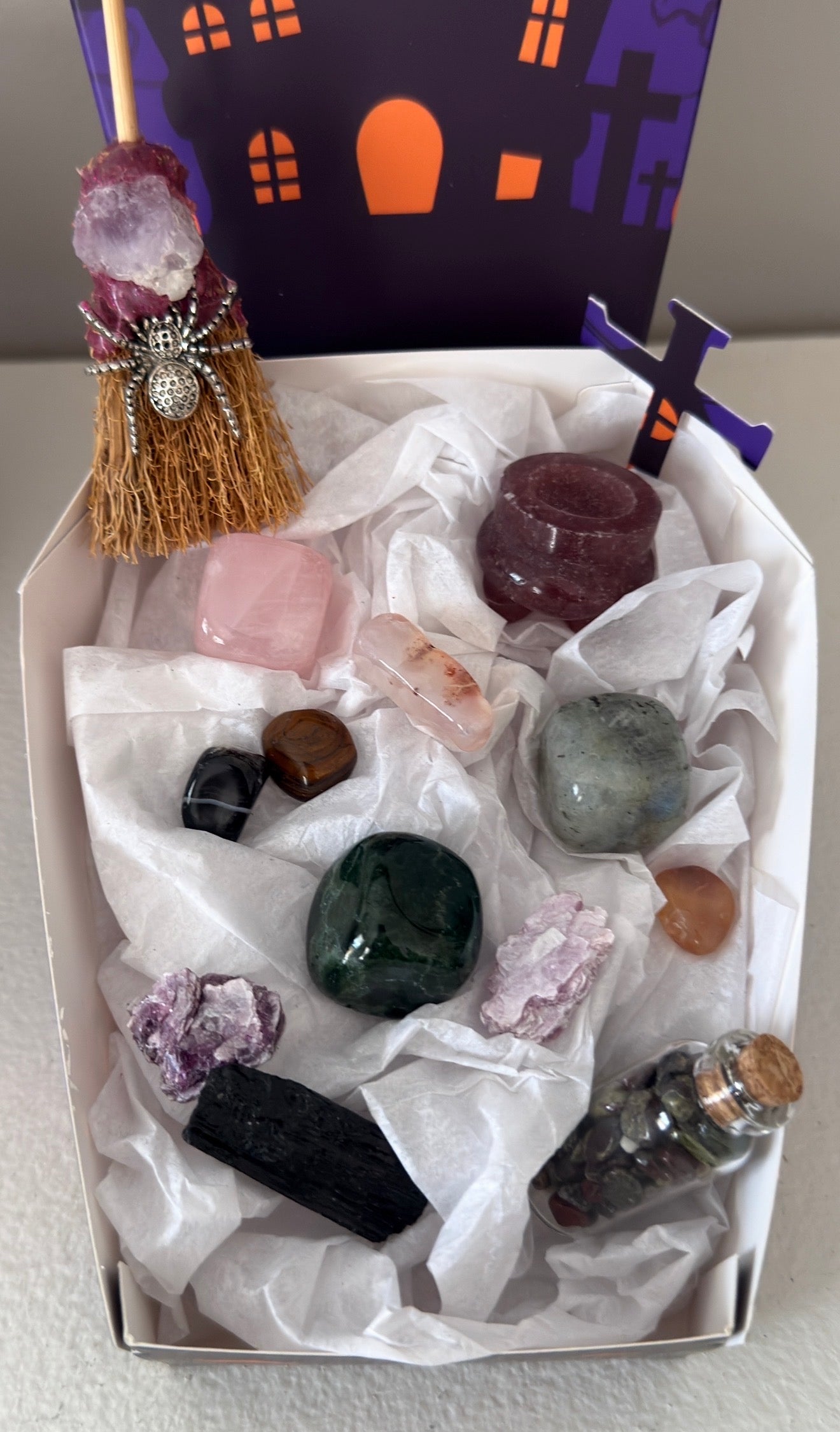 photo showing close up of all pieces in the bundle, strawberry quartz, rose quartz, green jasper, labradorite, black tourmaline, mica. Witches broom with amethyst and spider charm.  Assorted tumbles and wish bottle filled with dragon’s blood crystal chips