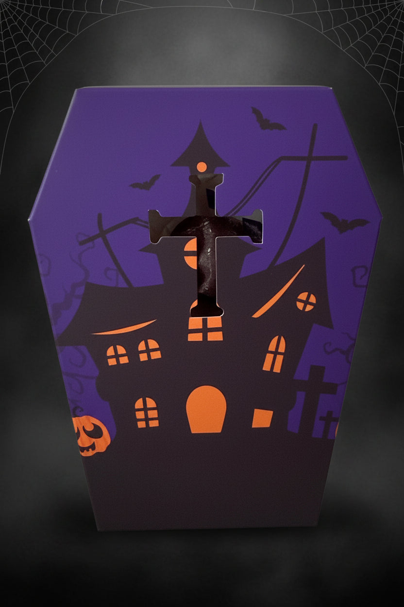 close up image of front of the coffin shaped specialty paper box included. purple and orange halloween house, bats and jack o lanterns  with a punched out cross three d effect 