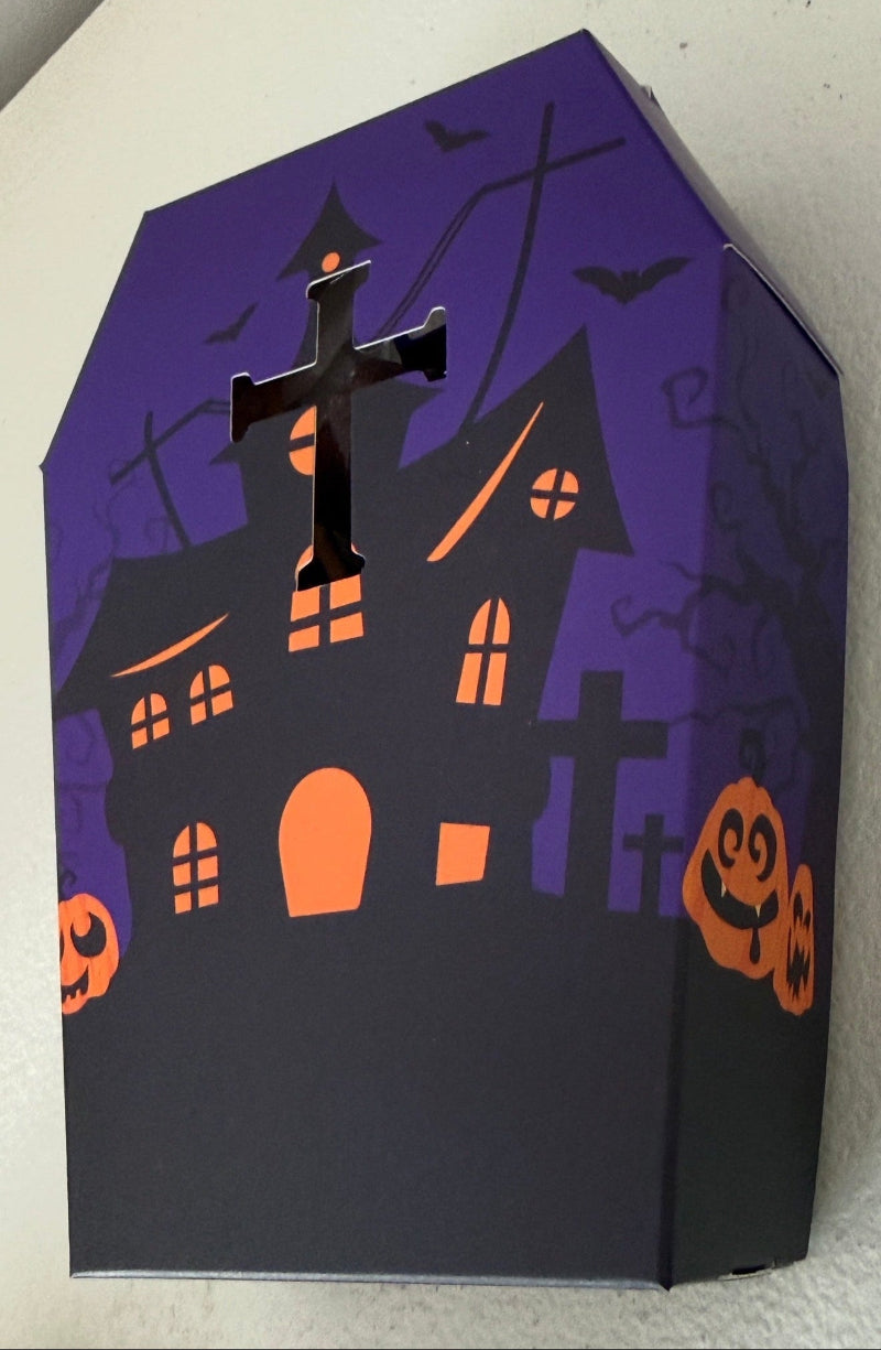 side view of specialty paper two piece box lid included.  Purple and orange halloween colors decorated with a spooky style black house, jack o lanterns, bats and crosses as tomb stones.