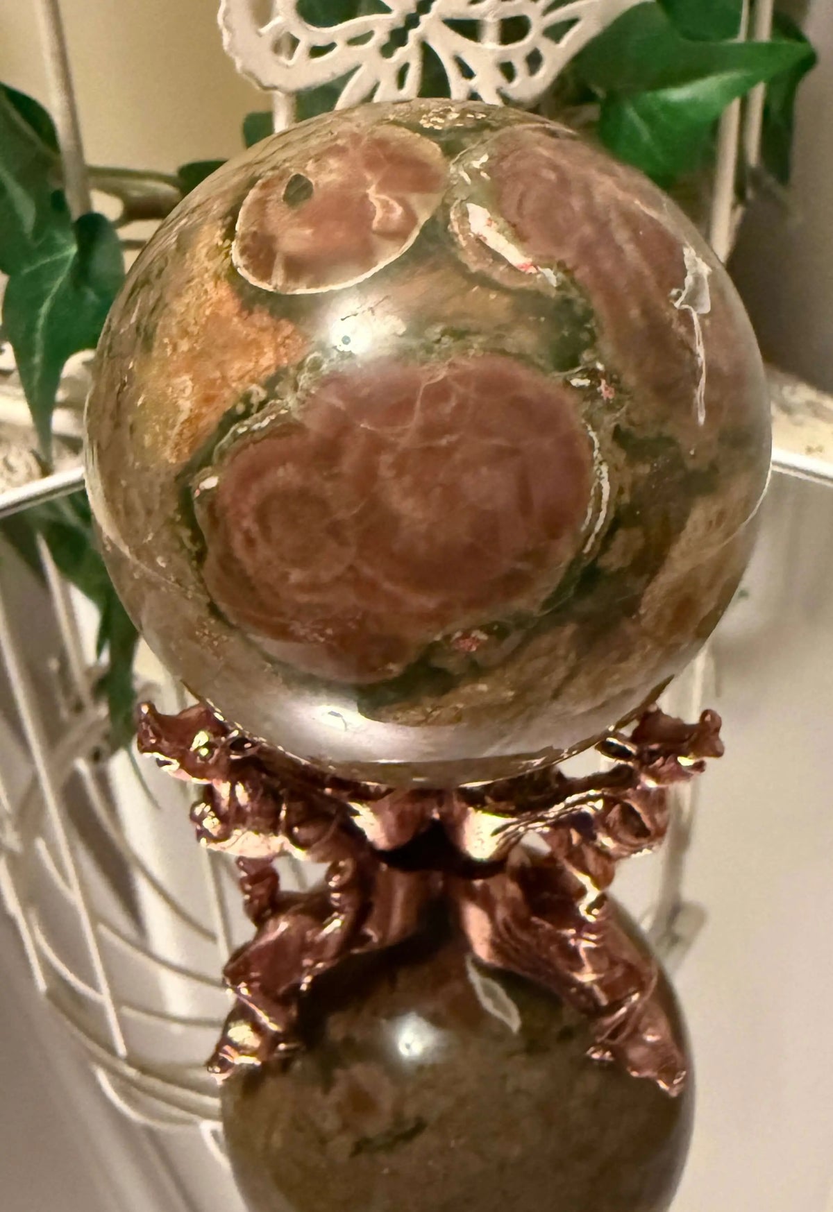 Close up Ocean jasper sphere on a Brass three leg stand and mirror table