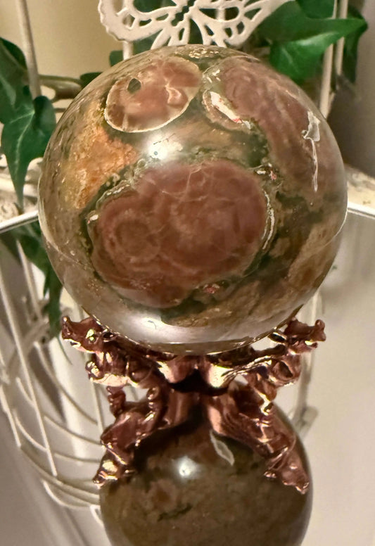 Close up Ocean jasper sphere on a Brass three leg stand and mirror table