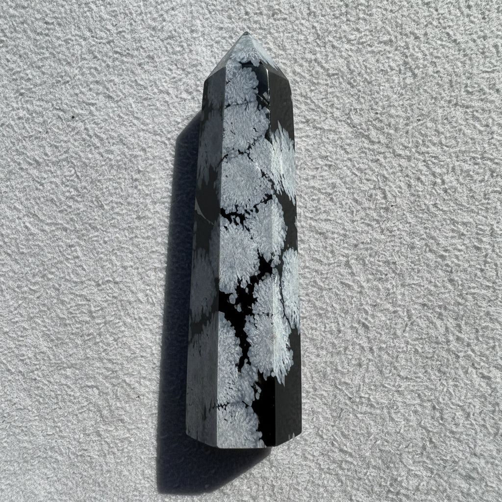 product photo gray and black carved hex tower made from snowflake obsidian crystal  background is simple white