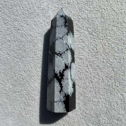 product photo gray and black carved hex tower made from snowflake obsidian crystal  background is simple white