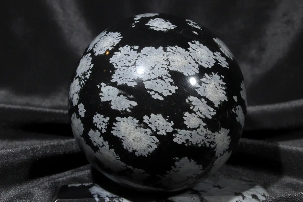 product photo black obsidian sphere black and gray with snowflake spots. 