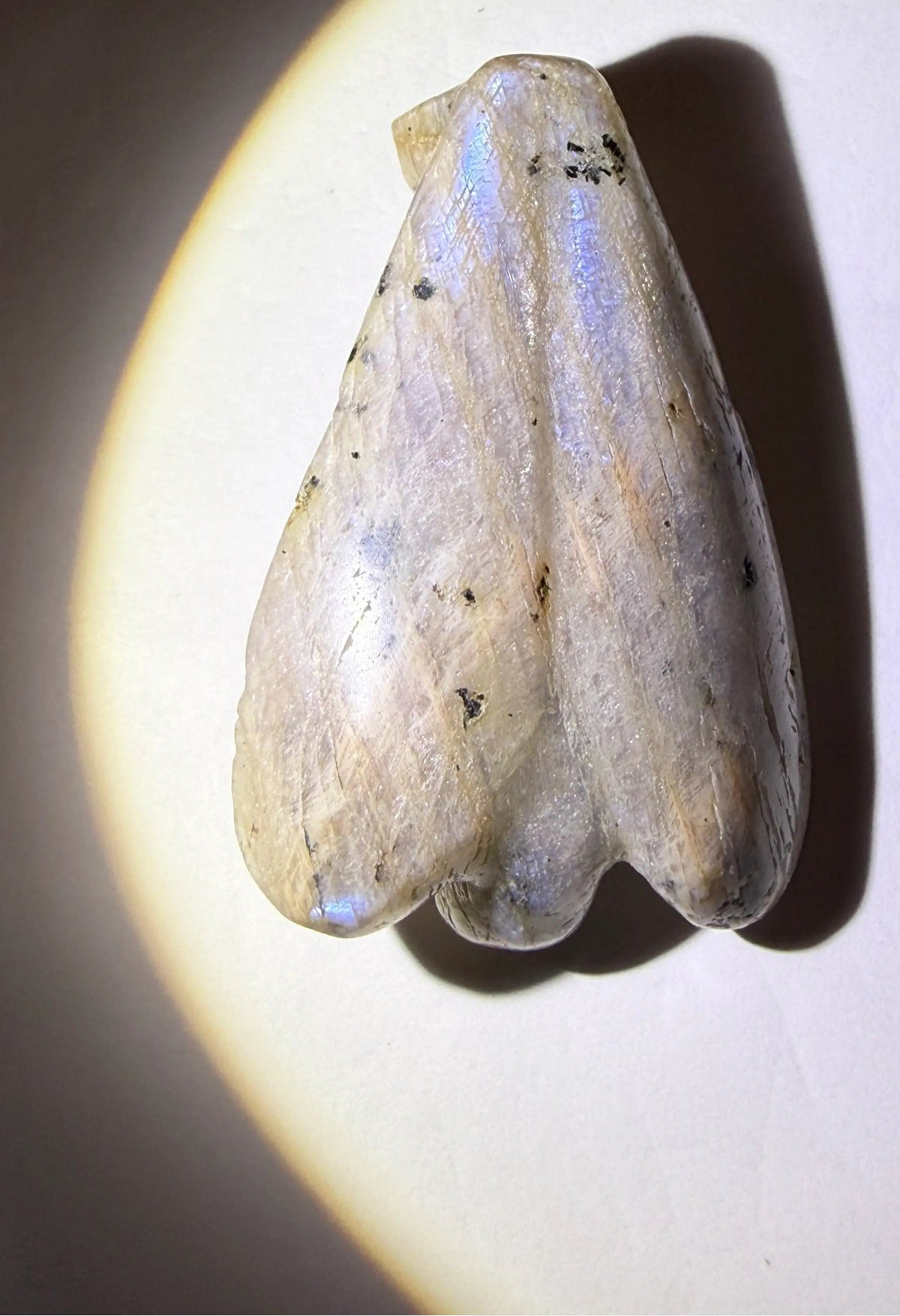 photo of the back rainbow moonstone carved angel figurine with soft blue adularescence
