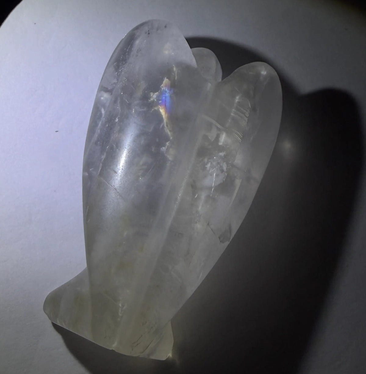 photo of the back of a carved angel.  Carved from natural clear quartz with a rainbow on the wing