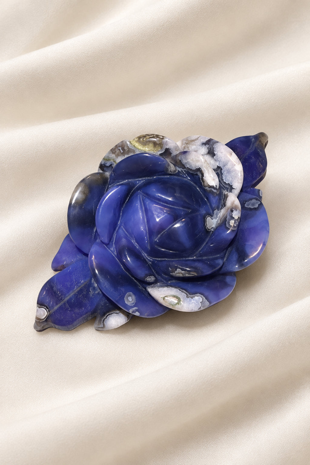 rose figurine carved from blue flower agate showing deep blues and light blues.  white flower patterns throughout